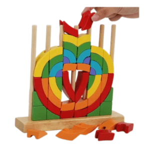 la boîte de jeu éducatif pour enfants "Wood mom Annular Rainbow Building Blocks". La boîte blanche et colorée montre le jouet assemblé : des anneaux en bois aux couleurs de l'arc-en-ciel empilés sur une base en bois avec des chevilles. Le produit est destiné aux 36 mois et plus et met en avant le développement de la mémoire, de la motricité fine et de la logique des couleurs.