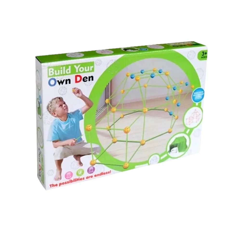 Gros plan sur la boîte d'un kit de construction pour enfants appelé "Build Your Own Den" (Construisez Votre Propre Cabane). La boîte montre un jeune garçon blond en train d'assembler une structure en forme de dôme à l'aide de tiges vertes et de connecteurs jaunes et bleus. L'inscription "3+ AGES" et "The possibilities are endless!" (Les possibilités sont infinies !) est visible.