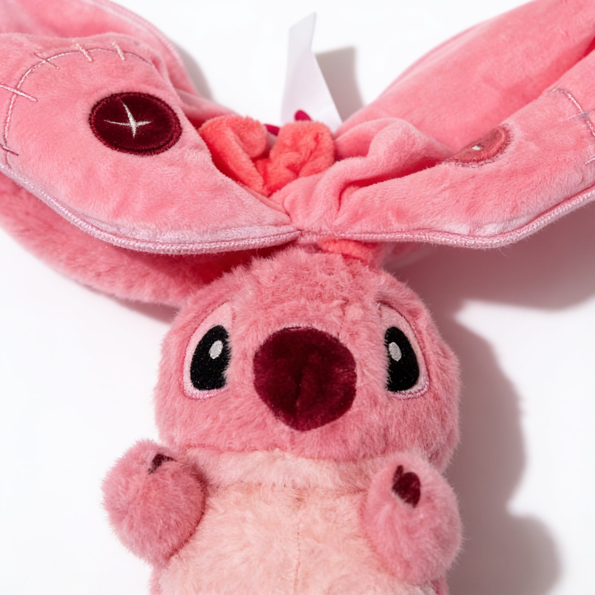 Détail de la peluche rose oreilles Détail des coutures visibles sur les oreilles de la peluche rose oreilles longues